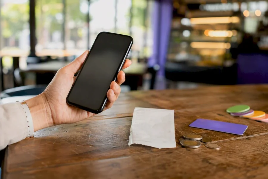 Hand holding smartphone with loyalty receipt nearby