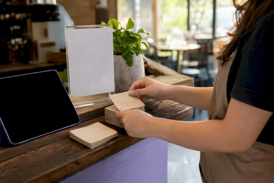 Mano configurando tarjetas de sellos de fidelización en un pequeño mostrador de tienda