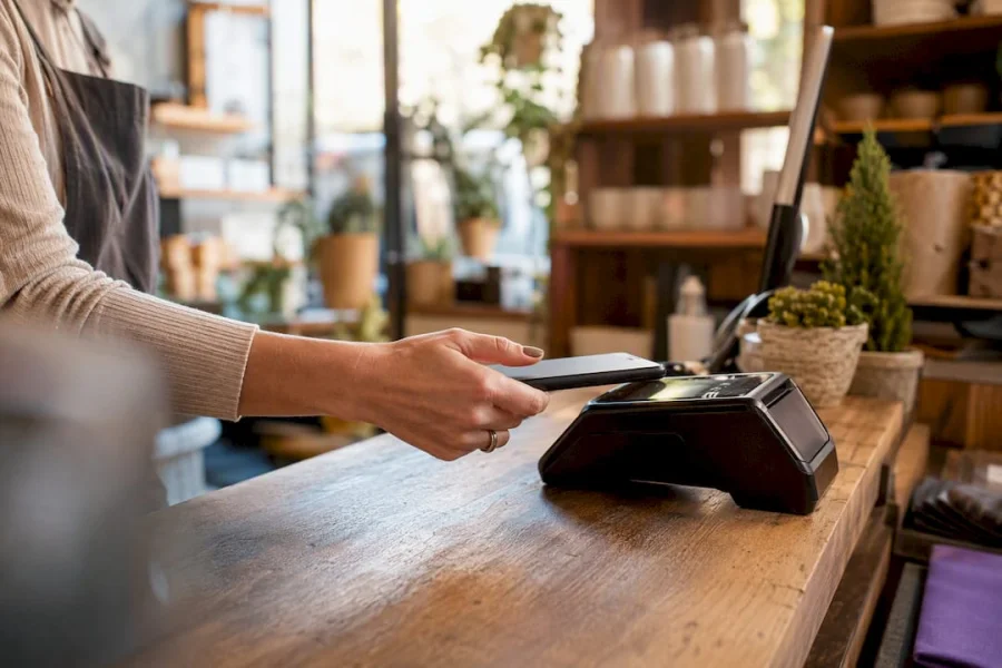 Manos tocando un tel&eacute;fono para ganar puntos de fidelizaci&oacute;n en un terminal de venta